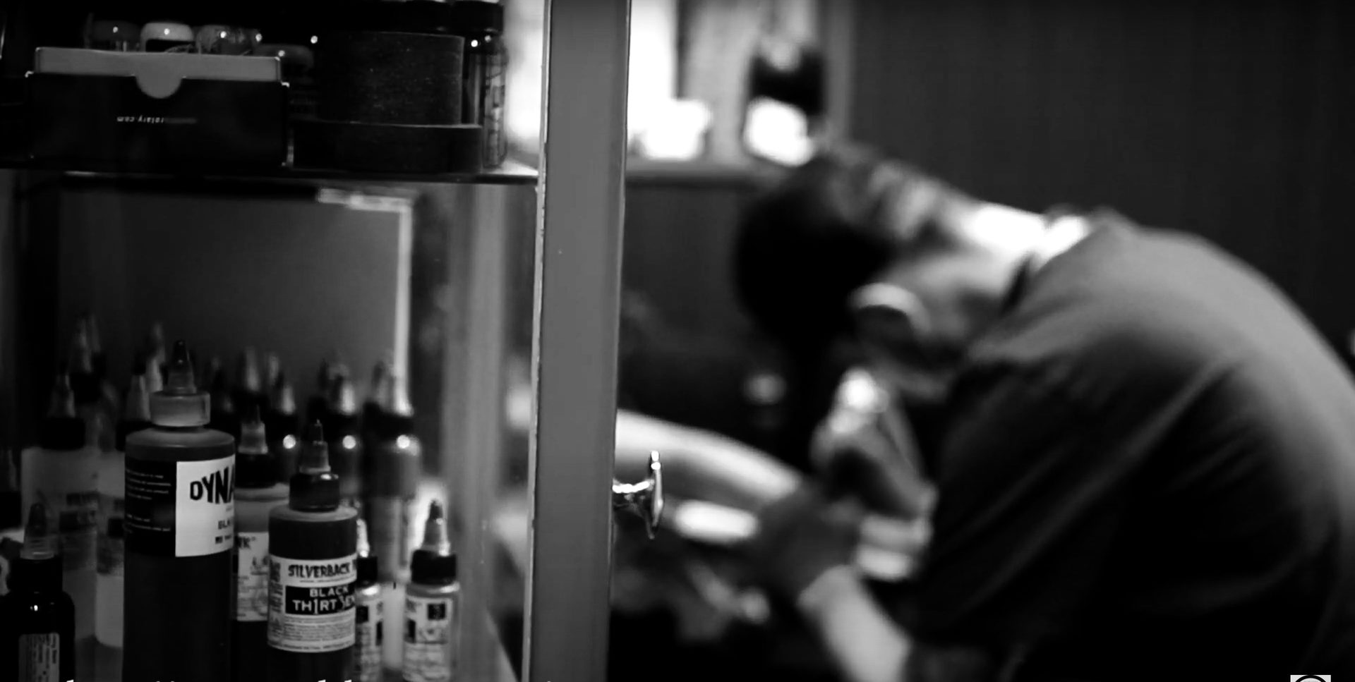 Black and white photo of Magnus tattooing at the studio